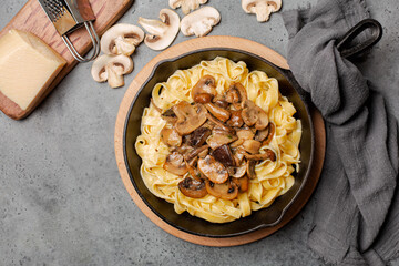 Pasta fettucine with mix of mushrooms on grey stone background.