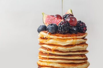 Pancakes with figs, berries and flowing honey. Homemade. Close-up. Light background.