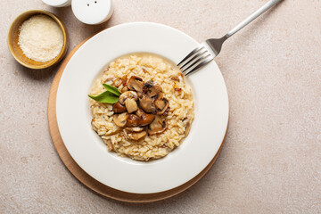 A plate of risotto with mix of mushroom and taleggio cheese on stone beige table.  Top view. Copy space