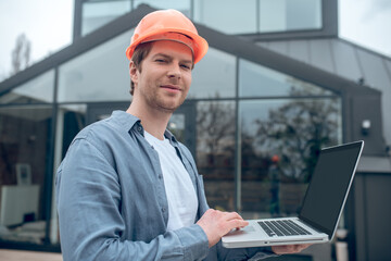 Happy man in safety helmet working on laptop