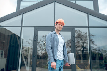 Man in protective helmet with laptop near building