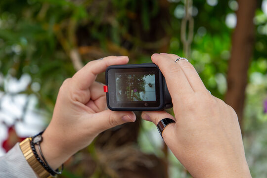 São Paulo, Brazil - 05,2021: Woman taking pictures of the garden with her new Gopro Hero 9