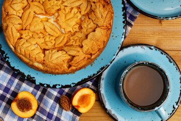 Closeup homemade pie with nectarines and cup of tea on wooden table. Top view.
