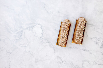 Beautiful eclairs on a light marble background. delicious pastries close-up.