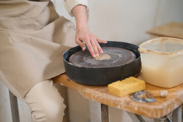 Obraz na płótnie Canvas Female potter working on a pottery wheel in workshop