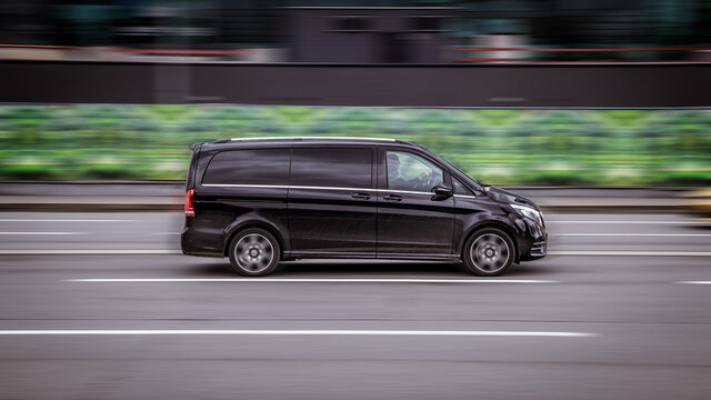 Black van Mercedes-Benz W447 Viano in the city street in motion. Premium minivan car rushes on highway, side view