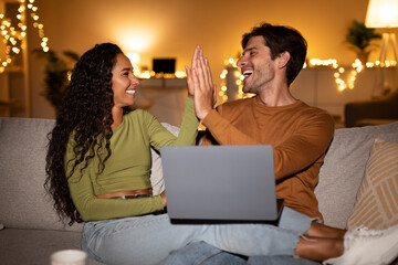 Joyful Couple Using Laptop Together And Giving High-Five At Home