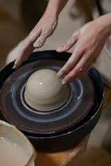 Close up of human hands molding clay on a pottery wheel