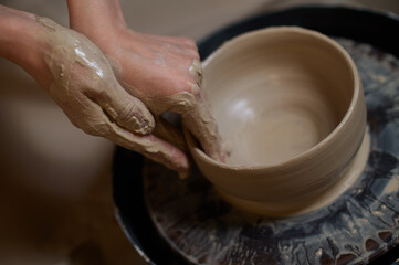 Close up of human hands making a bowl on a pottery wheel