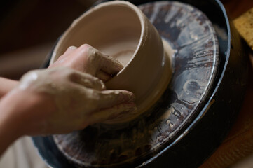 Close up of human hands making a bowl on a pottery wheel