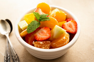Fruit salad with fresh apple, strawberry, tangerines, pineapple and honey. Diet and healthy eating