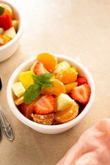 Fruit salad with fresh apple, strawberry, tangerines, pineapple and honey. Diet and healthy eating