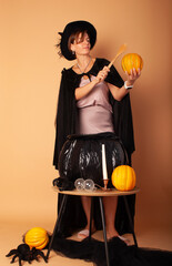 a woman in a witch costume conjuring over a cauldron depicting magic on Halloween with space for text in isolation on a beige background.