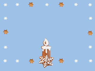 Gingerbread candlestick decorated with white icing in a frame from snowflakes and stars, isolated on blue background. Romantic Christmas greeting card, copy space for text