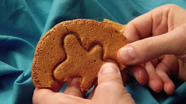 Men's hands break brown sugar caramel candy cookies in the shape of a men. Close-up of survival game