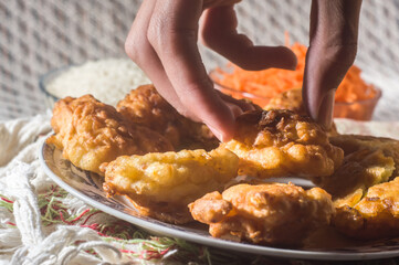 fried rice balls called bolinhos de arroz  on a plate with copy space and striped background, bowl with artos beans in the background and another bowl with grated carrots