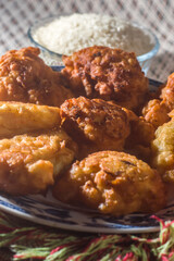 fried rice balls called bolinhos de arroz  on a plate with copy space and striped background, bowl with artos beans in the background and another bowl with grated carrots