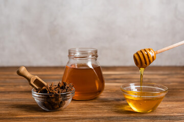 Fototapeta premium wooden dipper and scoop near jar and bowls with honey and anise seeds on grey marble background