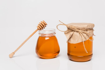 wooden dipper near jars with yellow honey on white background