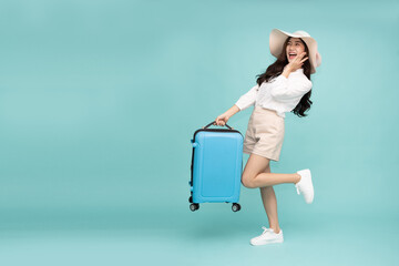 Happy Asian woman traveler standing and holding suitcase isolated on green background, Tourist girl...