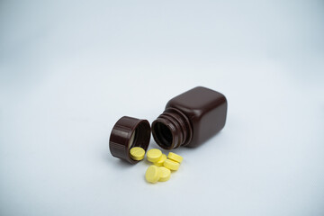 Brown pill bottle spilling pills on a white background