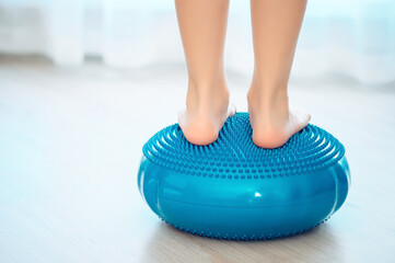 The child stands on a special inflatable pillow for the prevention and treatment of hallux valgus at home. Foot muscle training rear view