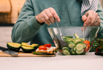 A man in the kitchen of the house cooks a healthy meal of vegetables with olive oil.