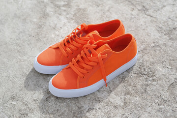 Orange sneakers for skateboarding on concrete floor.