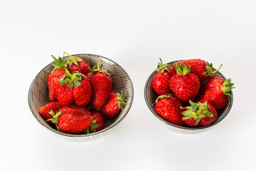 Strawberries in round plates, arranged on a white background.