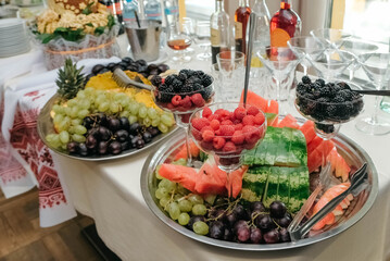 Berries and fruits in a glass dish and a tray on banquet table