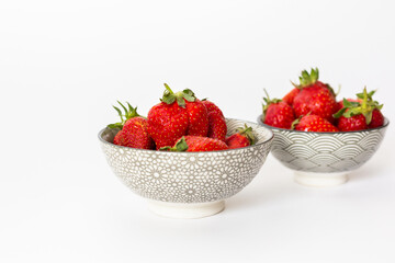 Strawberries in round plates, arranged on a white background.