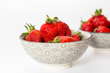 Strawberries in round plates, arranged on a white background.