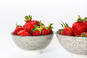 Strawberries in round plates, arranged on a white background.