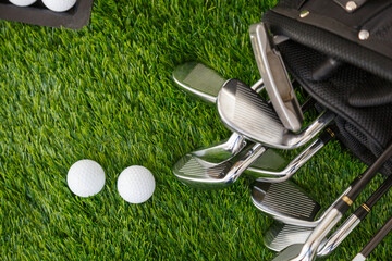 Metal golf clubs in a special black golf bag on the green grass of the golf course.