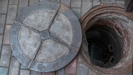 Blocked sewer drain. The water of recycling. Uninstalling septic tank with old iron manhole.