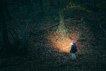 Woman holding flashlight hiking at night - obrazy, fototapety, plakaty