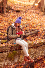 Woman reading a book outdoors on sunny autumn day