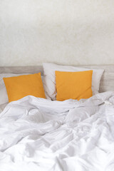 Fototapeta na wymiar Double bed in the bedroom with decorative yellow pillows and crumpled bed
