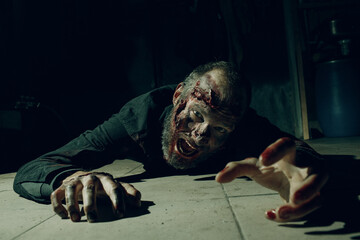 Zombie male creeps on floor halloween concept. Make up skin and blood face