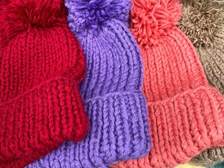 Fototapeta na wymiar Colorful wool knitted wool hats with pom-poms for cold winter weather.