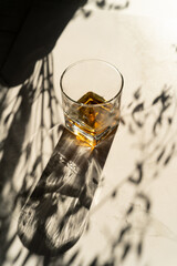 Still life of glass with whiskey or cognac. Glass of alcoholic drink with beautiful shadows and reflections on the surface