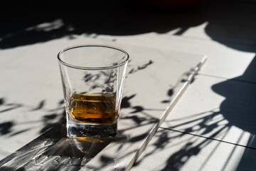 Still life of glass with whiskey or cognac. Glass of alcoholic drink with beautiful shadows and reflections on the surface