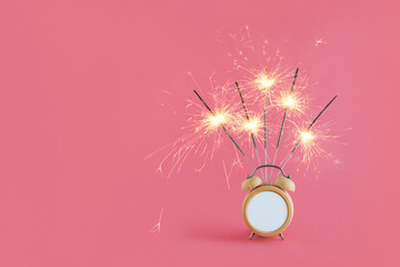 2022. Minimal abstract Christmas festive scene with alarm clock and sparklers isolated on pastel pink background. Celebration, anniversary or birthday concept. Party Invitation card idea.