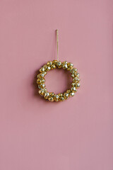 Stylish Christmas wreath of Golden bells on a pink background with copyi space