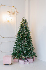 Elegant and beautiful Christmas tree in the interior of a bright living room. The Christmas tree is decorated with glass balls in the form of garlands