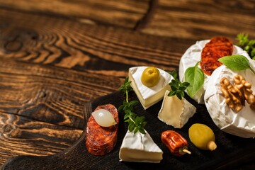 Camembert cheese on a rustic background. Noble cheese with mold. An overhead view of cheese with noble white mold and walnuts on a cutting board