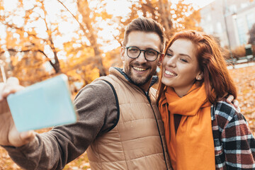Happy couple in autumn park make selfie photo.