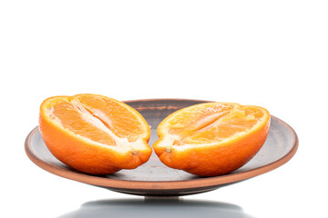 Two halves of organic ripe minneola on a ceramic dish, close-up, isolated on white.