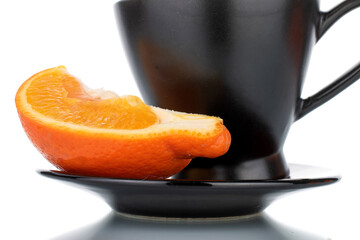 One slice of sweet organic minneola on a ceramic saucer with a cup, close-up isolated on white.