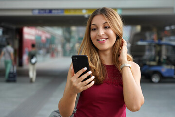 Charming beautiful business woman smile holds smartphone walking in train or metro station - obrazy, fototapety, plakaty